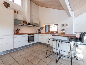 A modern kitchen with white cabinetry, a wooden countertop, and a large window.