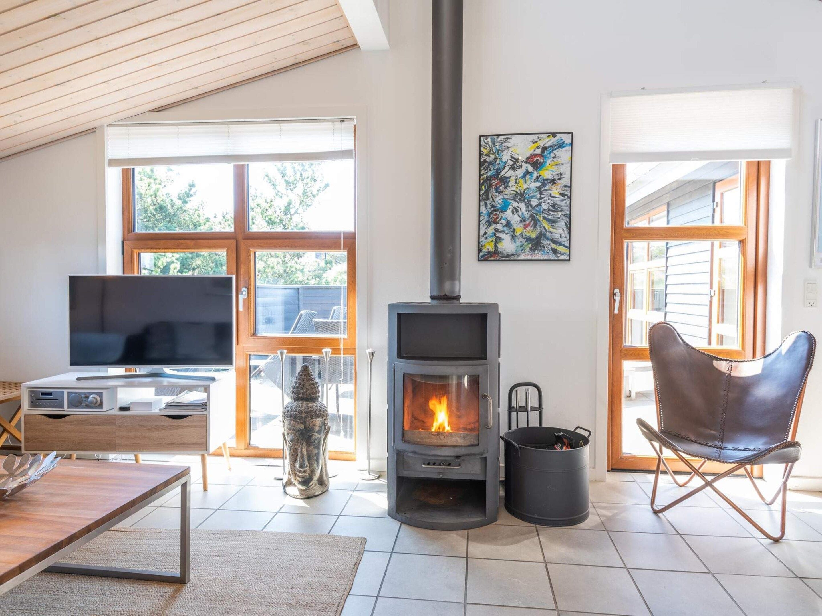 A living room with a wood-burning stove, a television, a statue, and a chair.