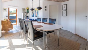 A spacious dining area with a round table, black chairs, and pendant lighting. - 5 Star Holiday Home in Fano (Fano)