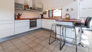 A modern kitchen with white cabinets, a wooden countertop, a built-in oven, and a window with a view. - 5 Star Holiday Home in Fano (Fano)