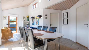 A modern dining area with a round table, chairs, and pendant lighting.