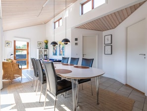 A modern dining area with a round table, chairs, and pendant lighting.