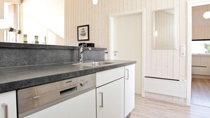 A modern kitchen with a granite countertop, stainless steel appliances, and white cabinetry. - Holiday Home in GroÃŸenbrode (Grossenbrode)