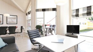 A modern living room with a white table, black leather chairs, a sofa, and a TV. - Holiday Home in GroÃŸenbrode (Grossenbrode)