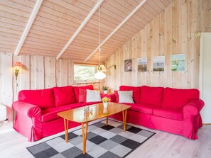 Una habitación con un sofá rojo, una mesa de madera y un tapete a cuadros.