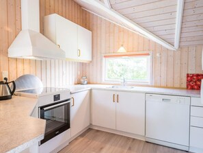 A modern kitchen with white cabinetry, a built-in oven, and a window above the sink.