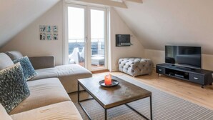 Un apartamento loft moderno con un ventanal grande, un sofá, una mesa de centro, un televisor y un balcón.