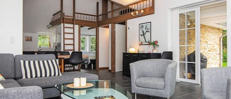 Una sala de estar moderna con una mesa de centro de vidrio, sofás grises y una escalera estilo loft.