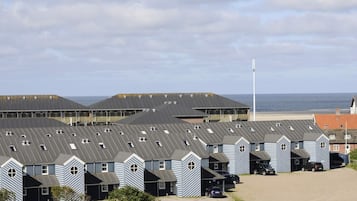 A coastal hotel with multiple buildings, each featuring a sloped roof and a series of windows.