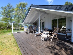 A covered outdoor deck with wooden chairs and tables, overlooking a grassy area with trees. - 4 Person Holiday Home in Fano (Fano)