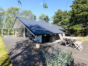 A wooden deck with a covered outdoor seating area, a small shed, and a garden with potted plants. - 4 Person Holiday Home in Fano (Fano)