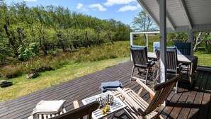 A covered outdoor deck with wooden furniture and a view of a vineyard. - 4 Person Holiday Home in Fano (Fano)
