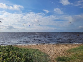 Una playa con vistas al mar y al cielo, con una orilla arenosa y algo de vegetación.