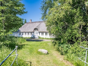 A white house with a thatched roof, surrounded by lush greenery and a clear sky. - 6 Person Holiday Home in Hemmet (Hemmet)