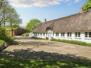 A traditional thatched-roof house with a gravel driveway and a stone wall on one side. - 6 Person Holiday Home in Hemmet (Hemmet)