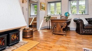 Un salón acogedor con chimenea, suelo de madera, un sofá de cuero y un escritorio con un globo terráqueo.