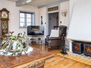 Uma sala de estar com televisão, lareira, relógio e janela.