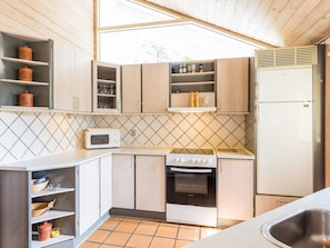 A compact kitchen with wooden cabinets, a microwave, an oven, and a refrigerator.