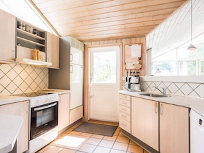 Compact kitchen with oven, stovetop, sink, coffee maker, and refrigerator.
