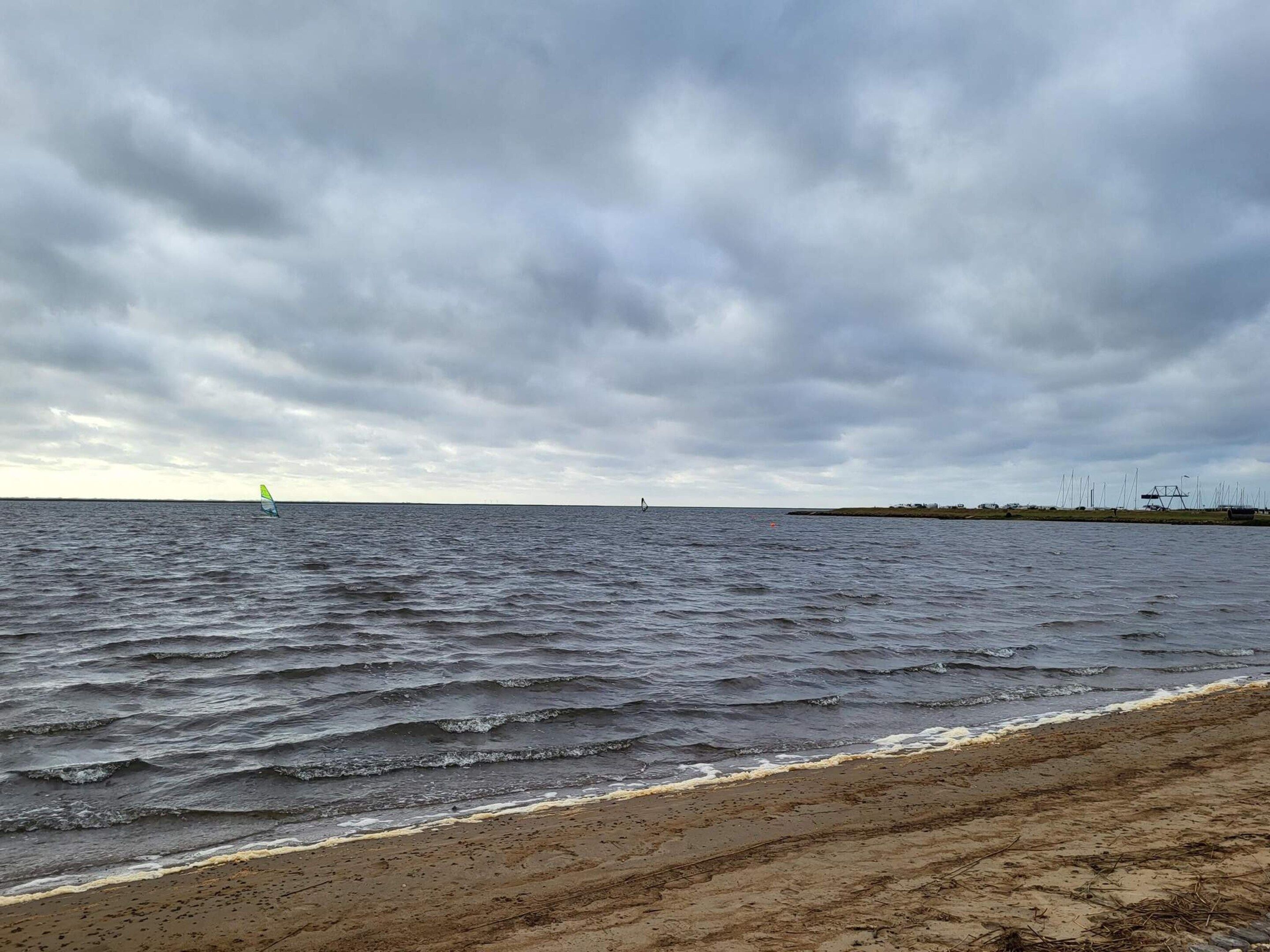A beach with a sandy shore and a view of the sea under a cloudy sky.