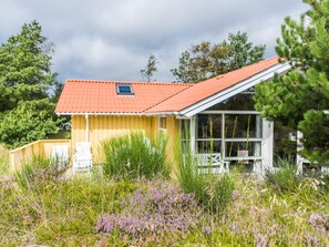 Un bâtiment jaune avec un toit rouge, entouré de verdure et d’arbres.