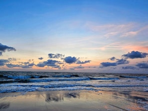 Une plage avec des vagues et un ciel au coucher du soleil.