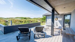 A wooden deck with two lounge chairs and a bench, overlooking a grassy landscape. - Holiday Home in Henne (Henne)