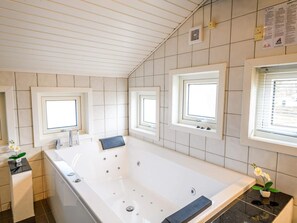 A modern bathroom with a large bathtub, three windows, and a tiled ceiling. - 6 Person Holiday Home in Fano (Fano)
