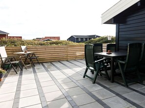 A patio with a wooden fence, outdoor seating, and a view of neighboring houses. - 5 Person Holiday Home in Fano (Fano)
