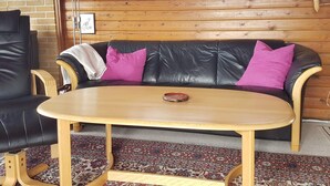 A cozy room with a black leather sofa, a wooden coffee table, and a patterned rug. - 5 Person Holiday Home in Fano (Fano)