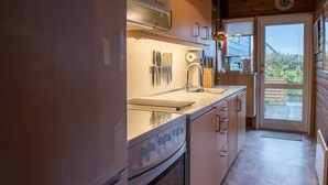 A modern kitchen with a built-in oven, a stainless steel sink, and a window overlooking a garden. - 5 Person Holiday Home in Fano (Fano)