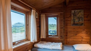 A small wooden cabin room with a single bed, two windows, and a painting on the wall. - 5 Person Holiday Home in Fano (Fano)