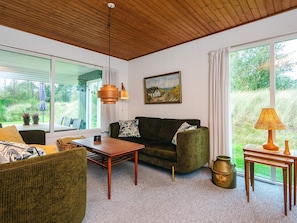 A cozy living room with a wooden ceiling, a green sofa, a wooden coffee table, and a painting on the wall. - 6 Person Holiday Home in Blavand (Blavand)