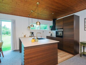 Una cocina moderna con una isla grande, armarios de madera e iluminación colgante.