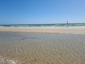 A beach with clear shallow waters and a flagpole in the distance. - 6 Person Holiday Home in Blavand (Blavand)