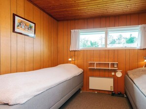 A room with wooden walls, a window with curtains, a bed, a bedside table, and a wall-mounted shelf. - 6 Person Holiday Home in Blavand (Blavand)