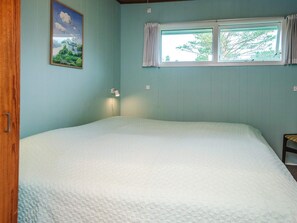 A room with a single bed, a window with curtains, a wall-mounted lamp, and a framed picture. - 6 Person Holiday Home in Blavand (Blavand)