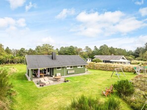 A green building with a tiled roof, a patio with outdoor furniture, and a grassy yard. - 6 Person Holiday Home in Blavand (Blavand)