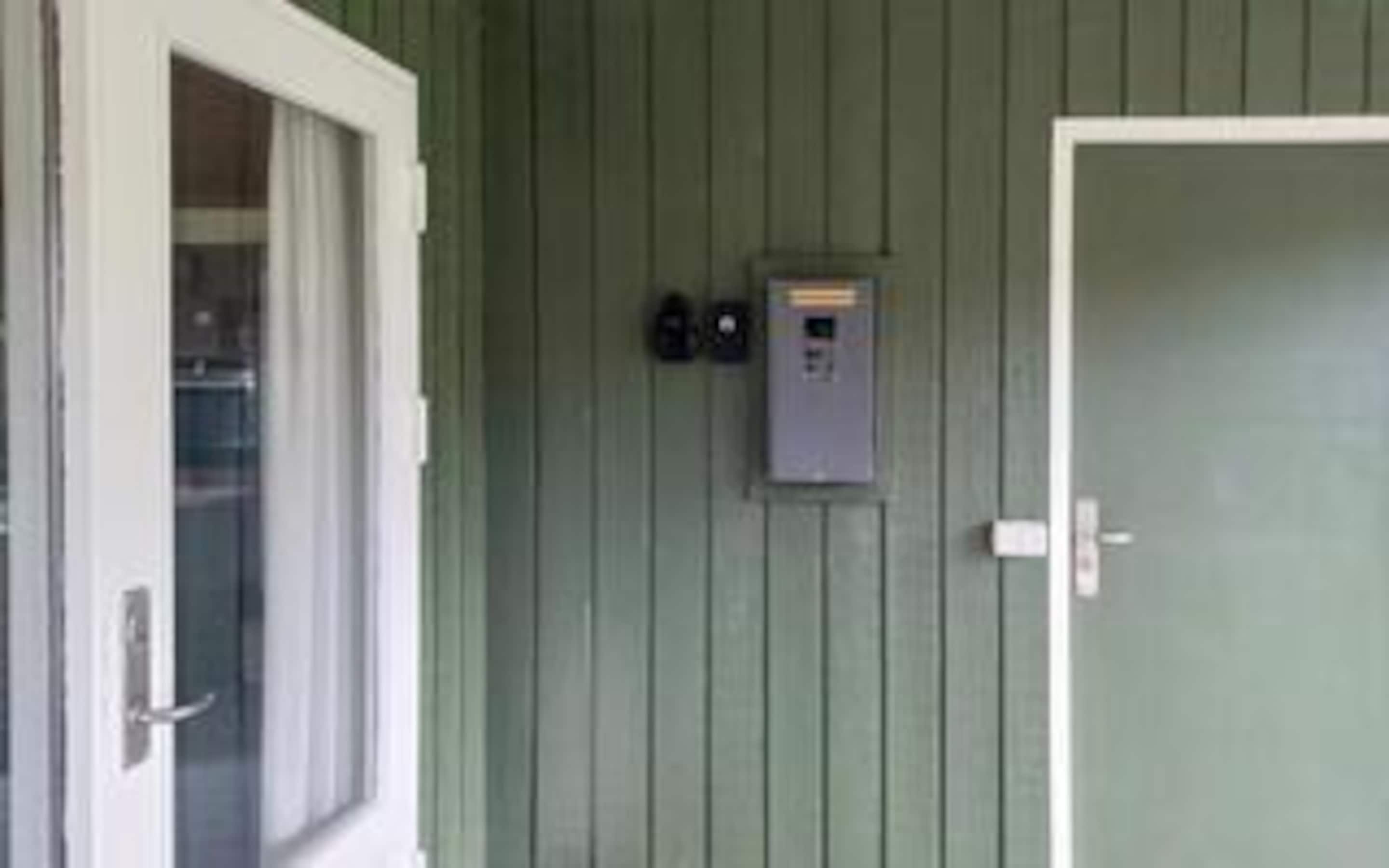 Eine Tür mit Glasfenster, ein an der Wand befestigtes Stromdosenfeld und ein Türgriff.