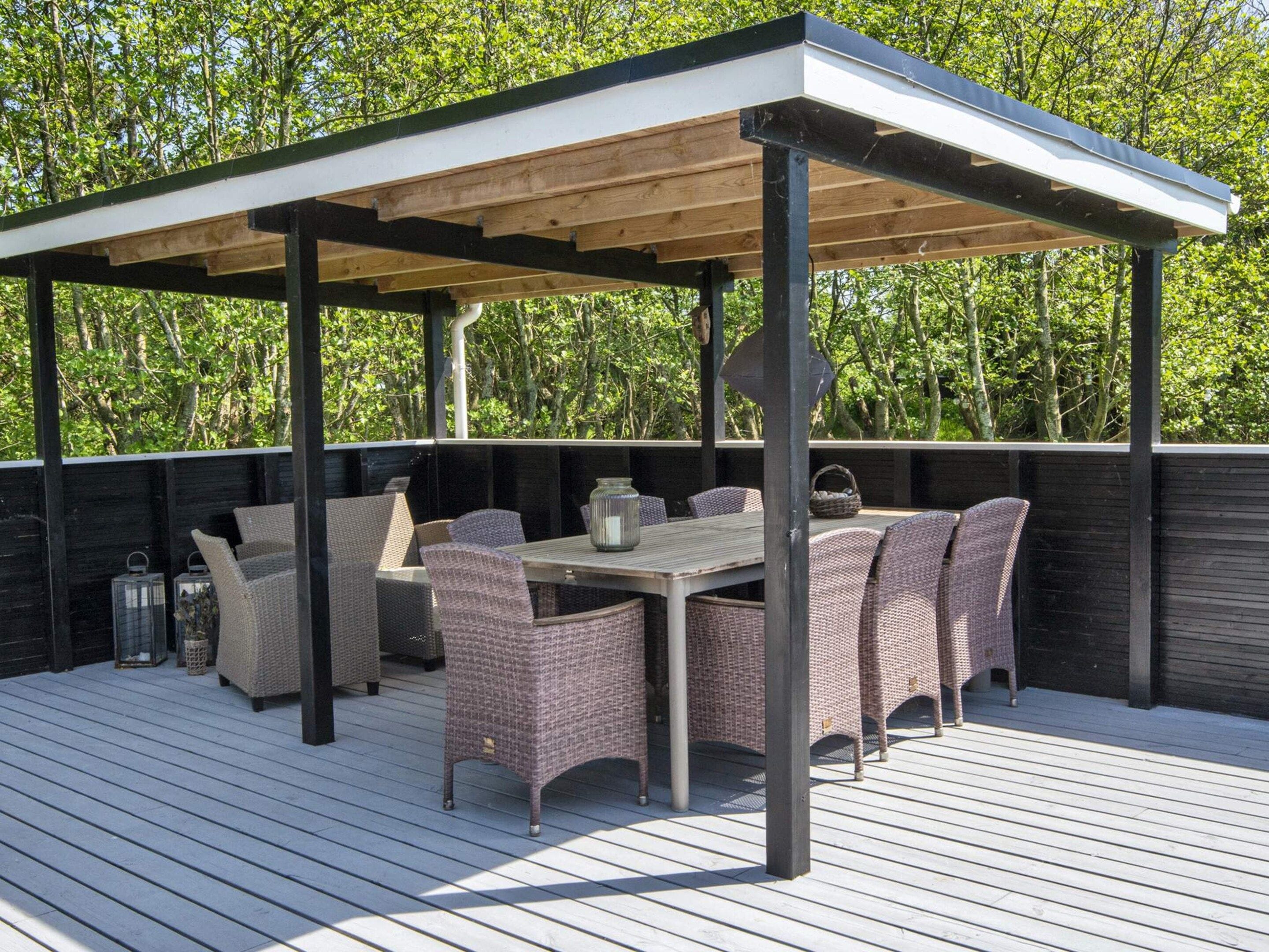 An outdoor patio with a covered seating area, a table, and wicker chairs.