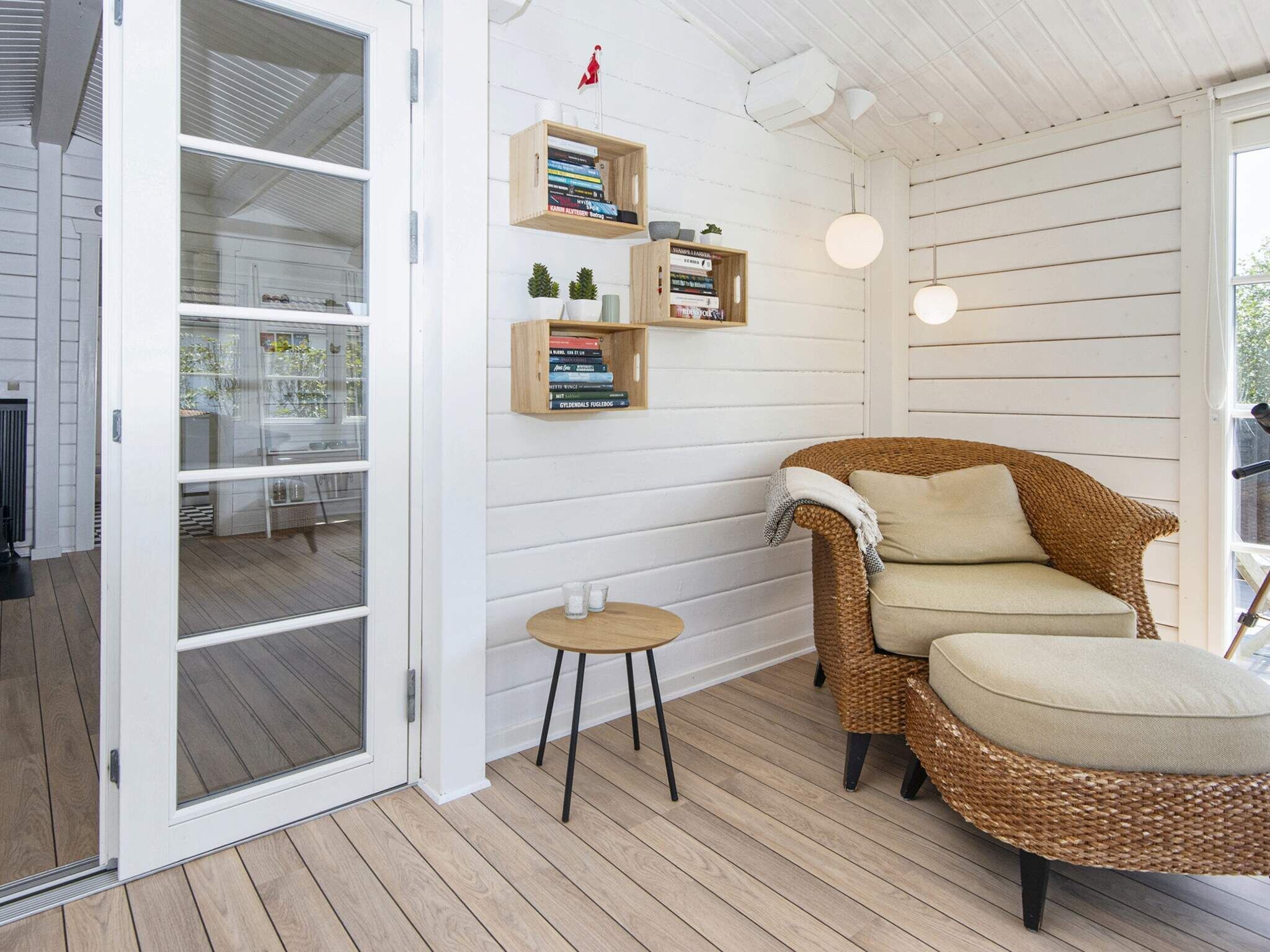 A cozy room with a wicker sofa, a small round table, and bookshelves against the wall.