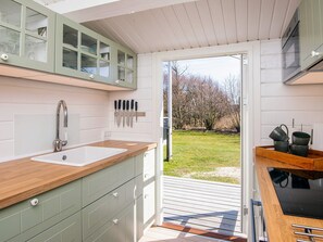 A modern kitchen with a wooden countertop, a sink, and a window overlooking a grassy area. - 5 Person Holiday Home in Fano (Fano)