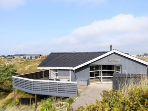 A modern house with a sloped roof, large windows, and a covered outdoor area. - Seaside Retreat in Rindby-by Traum (Fano)