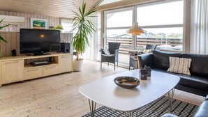 A modern living room with a TV, sofa, and dining table.