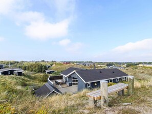 A modern house with a flat roof, a deck, and a wooden bench. - Seaside Retreat in Rindby-by Traum (Fano)