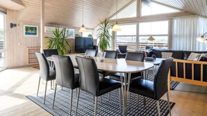 A modern dining area with a round table, black chairs, and a wooden ceiling.