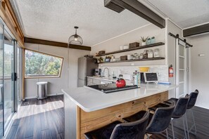 Une cuisine moderne dotée d’un grand îlot central, de touches de bois et offrant une vue sur l’extérieur.