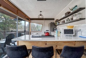 Une cuisine moderne dotée d’un grand îlot central, de meubles en bois et offrant une vue sur l’extérieur.