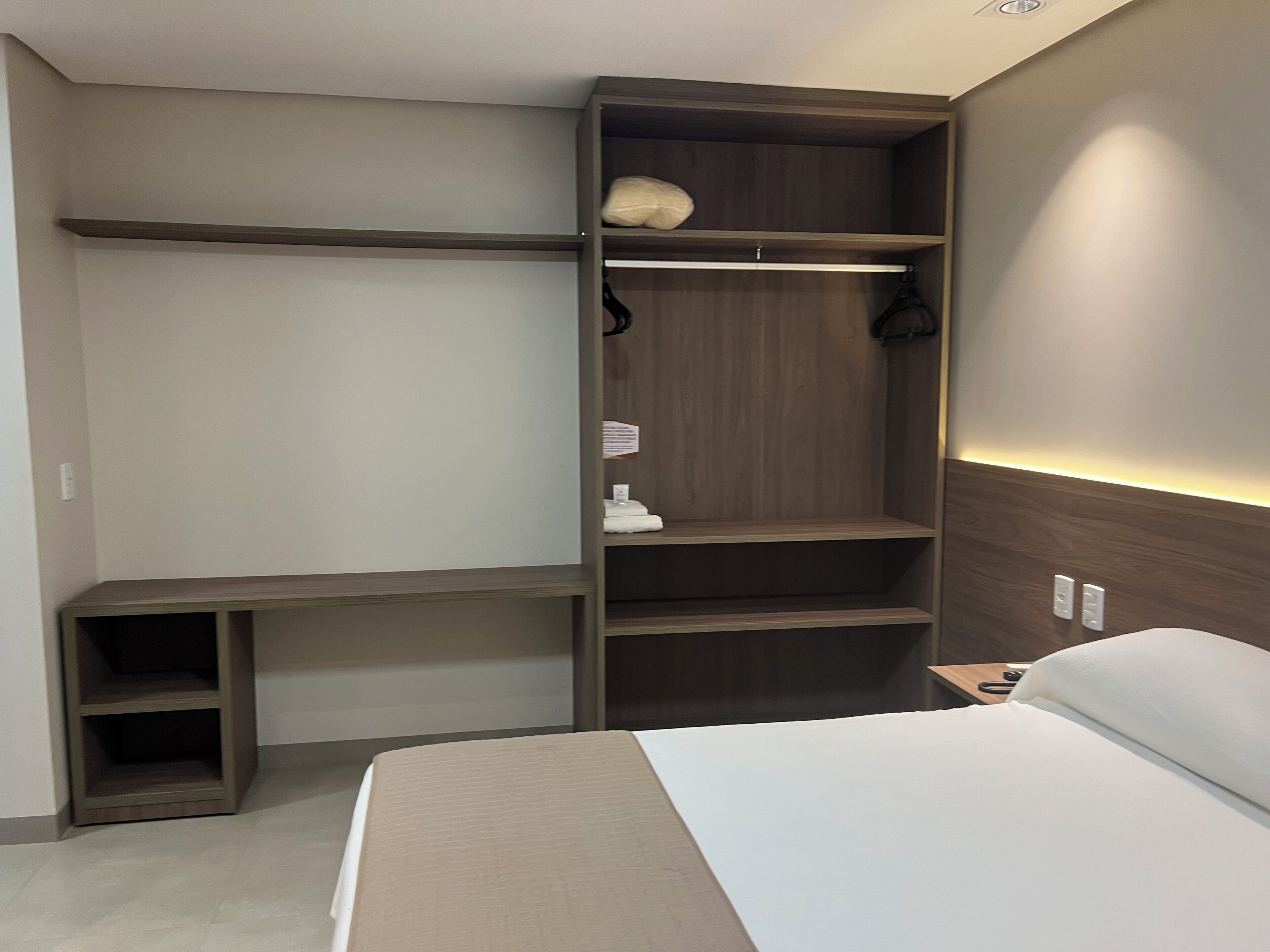 Ein Schlafzimmer mit einem Bett, einem Schrank mit Einlegeböden und einem Nachttisch.