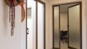 A hallway with a wooden floor, a wall-mounted plant, and two decorative vases.